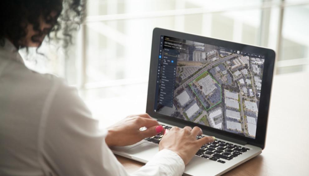 A person using a laptop showing a map with data overlays